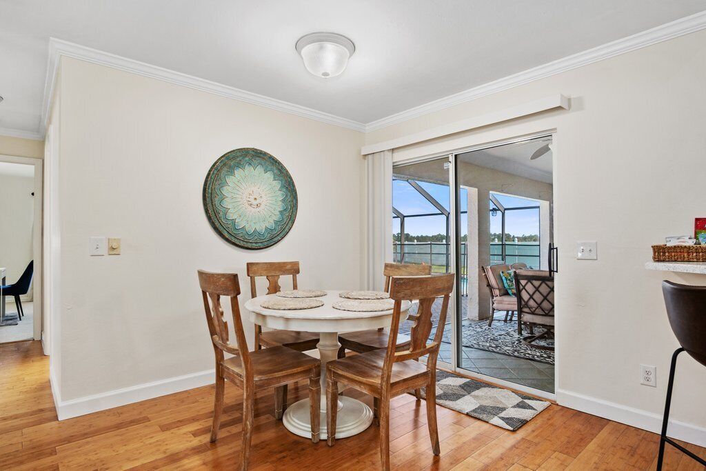 Un coin repas avec une table ronde, des chaises en bois et une assiette décorative accrochée au mur.