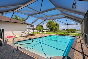 A covered swimming pool with a geometric roof structure, lounge chairs, and a view of the surrounding landscape. - Feel @ Home Ft Myers - 3bd - 2bh - POOL - Sleeps 8 (Fort Myers)