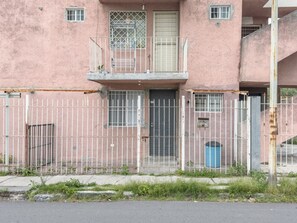 Ein pinkfarbenes Gebäude mit einem ehrvervollen Eingang, einem Balkon und einer Mülltonne.