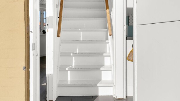 Eine weiße Treppe mit Holzgeländern, die zu einer Tür führt.