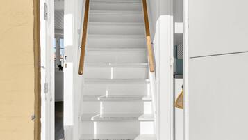 Un escalier blanc avec des rampes en bois menant à une porte.