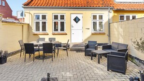 Ein gelbes Gebäude mit rotem Ziegeldach, einer weißen Tür und einem kleinen Fenster.