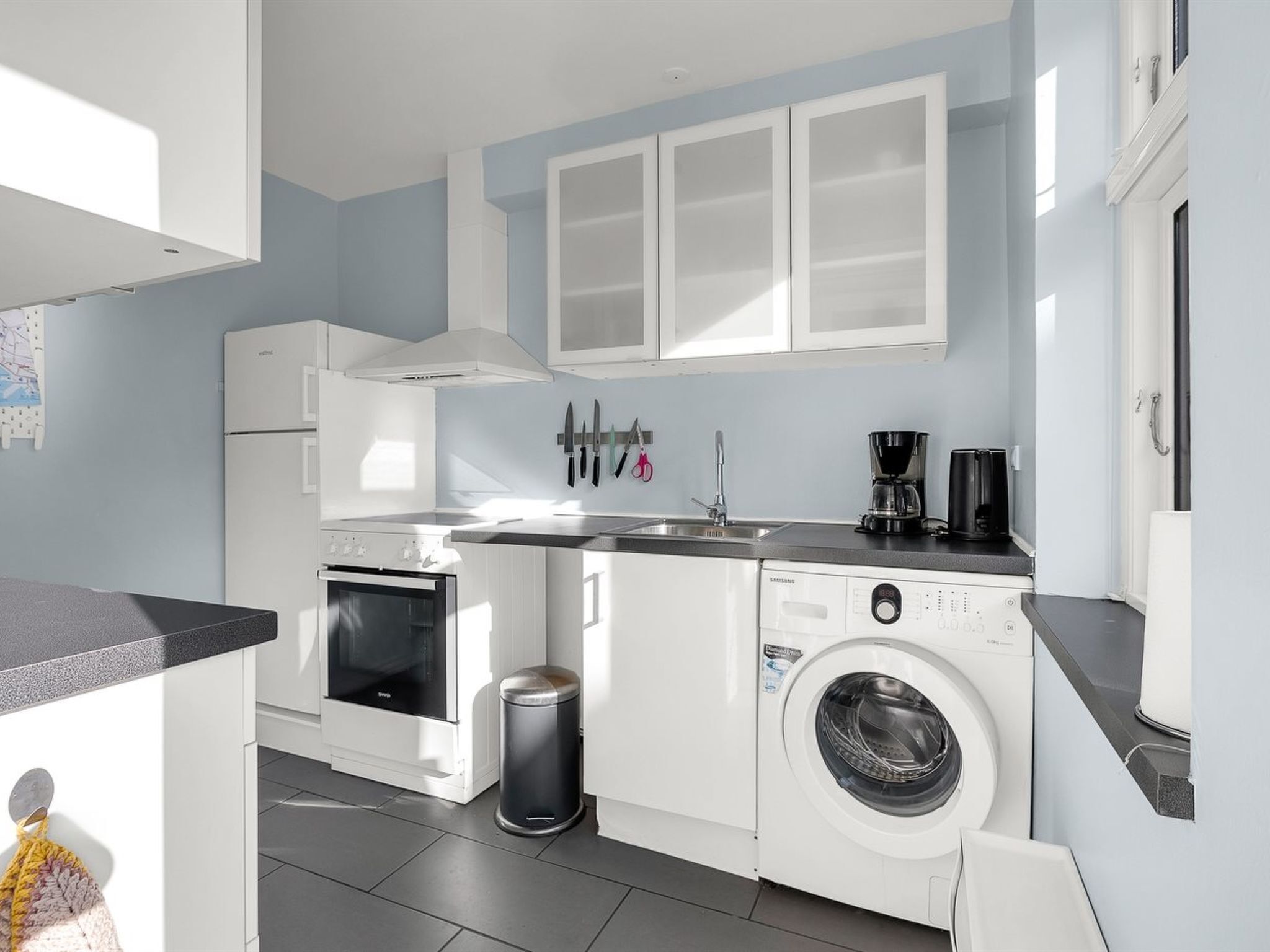 Une cuisine de taille réduite équipée d’un lave-linge, d’une cuisinière et d’un évier.