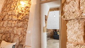 A stone wall interior with a doorway leading to a living area with a sofa and a table. - Le Terrazze Del Sud - Salve (Salve)