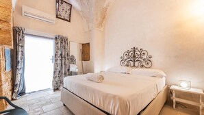 A bedroom with a large bed, a bedside table with a lamp, a chair, and a view of the outside. - Le Terrazze Del Sud - Salve (Salve)