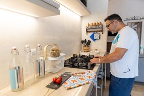 A kitchen with a gas stove, a basket with herbs, and a shelf with kitchen utensils. - Villa Terra E Sale - Salve (Salve)