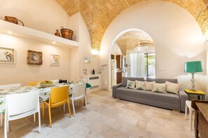 A dining area with a table set for two, a sofa, and a lamp. - Villa Terra E Sale - Salve (Salve)