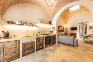 A spacious kitchen with an arched ceiling, wooden cabinets, and a dining area with a table and chairs. - Villa Terra E Sale - Salve (Salve)