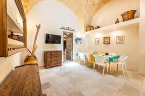 A dining area with a table, chairs, and a TV mounted on the wall. - Tenuta Terra E Sale - Salve (Salve)
