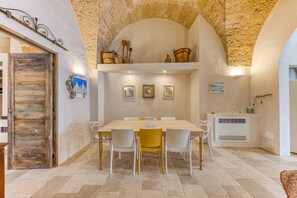 Un'area pranzo con soffitto in pietra, una porta in legno e un tavolo con sedie.