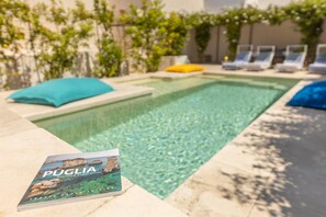 A swimming pool with lounge chairs and a book titled 'PUGLIA Routes & Experiences' on the edge. - Tenuta Terra E Sale - Salve (Salve)