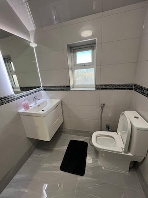 Un baño moderno con inodoro, lavamanos y ventana.