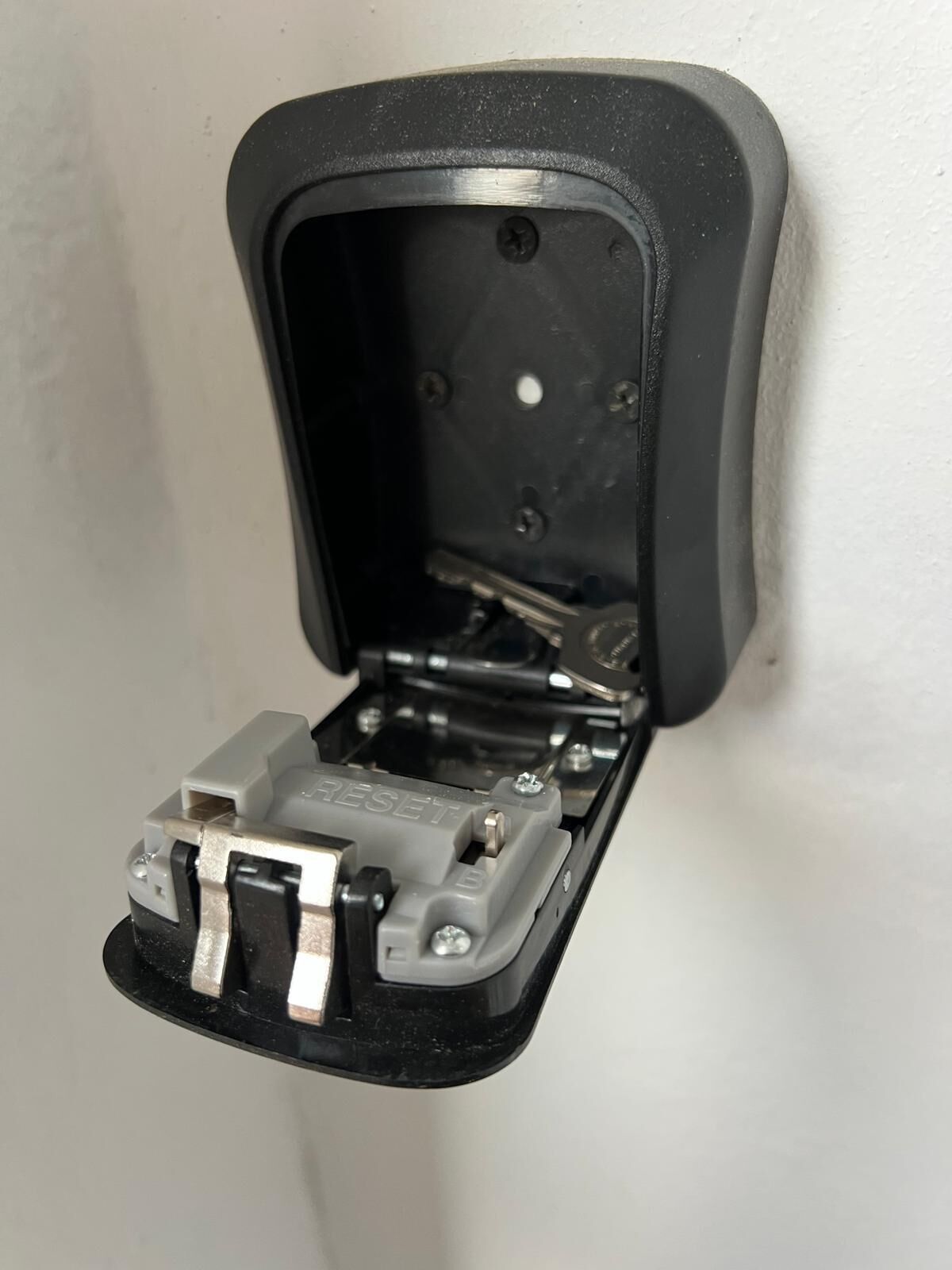Ein schwarzer, offener Stromverteiler mit sichtbaren Schrauben und einem Reset-Knopf.