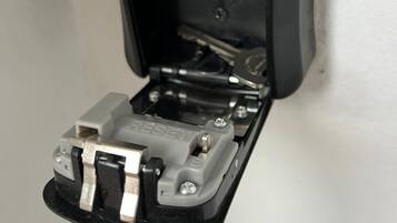 Caja eléctrica negra abierta con tornillos visibles y un botón de reinicio.