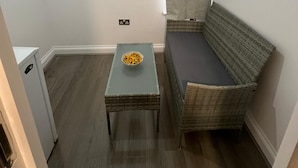 A small room with a grey sofa, a wicker table with a bowl of fruit, and a white cabinet.