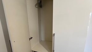 A white closet with a sliding door, a hanging rod, and a built-in shelf.