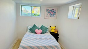 Un dormitorio con cama, almohadas, un cuadro enmarcado y una ventana.
