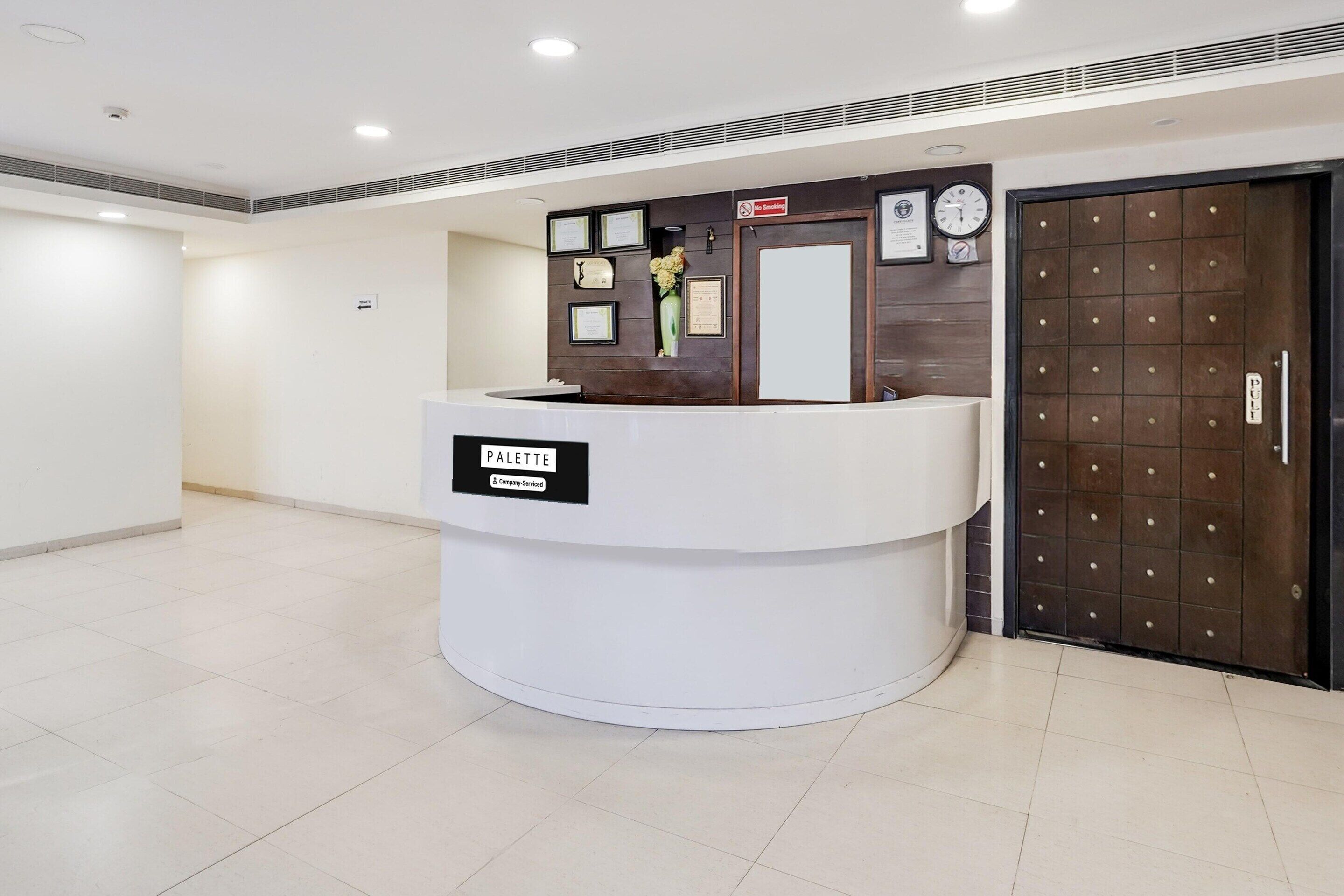 A reception desk labeled "PALETTE" with a clock and framed certificates on the wall.