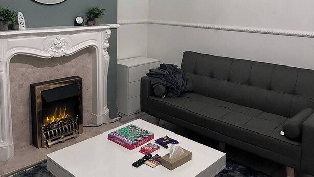 Ein Wohnzimmer mit Kamin, einer Couch, einem Couchtisch mit Gesellschaftsspielen, einem Spiegel und einer Chandelier.