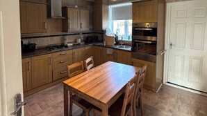 Eine Küche mit Holzausstattung, einem Esstisch mit Stühlen und einem eingebauten Backofen.