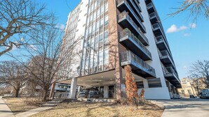A multi-story building with a covered entrance, a parking area, and a clear sky. - Wonderful 1BR Retreat with Balcony in Oak Park (Oak Park)