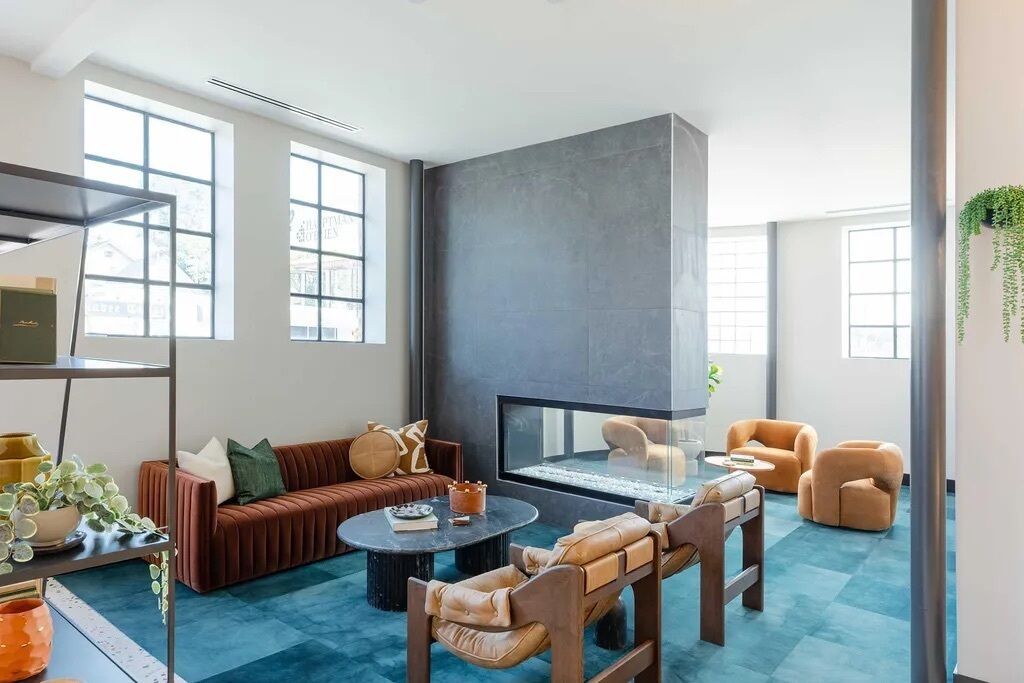 A modern living room with a sofa, armchairs, a coffee table, and a fireplace.