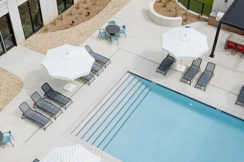 A pool area with lounge chairs, umbrellas, and a clear blue pool.