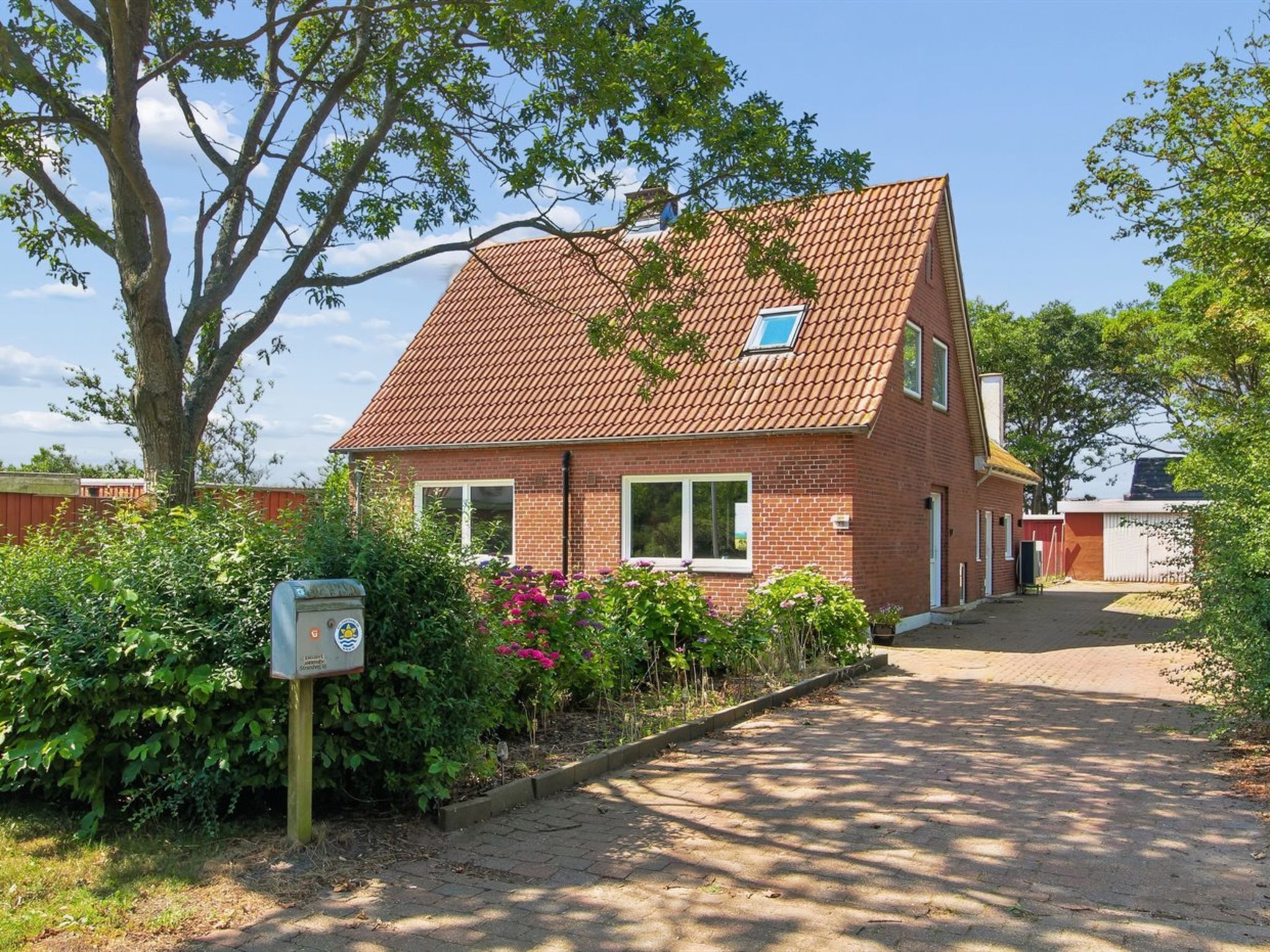 Une maison en briques avec un toit en tuiles, une petite fenêtre et un jardin fleuri.