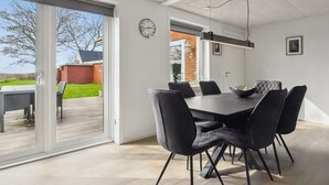 A modern dining area with a large table and chairs, a clock on the wall, and a view of the outdoors. - "Milan" - 20km from the sea by Interhome (Bredebro)