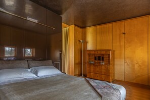 Un dormitorio con una cama grande, un armario de madera y una lámpara de pie.
