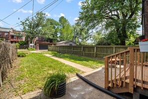 A backyard with a wooden deck, a concrete pathway, and a fenced area. - Benton Park Retreat - MO2S (St. Louis)