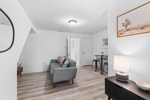 A modern living room with a grey sofa, a small round table, and a lamp.