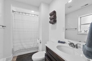 A modern bathroom with a shower curtain, toilet, sink, and a towel rack.