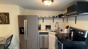 Une cuisine compacte équipée d’un réfrigérateur, d’un lave-vaisselle, d’une cuisinière et d’un four à micro-ondes.