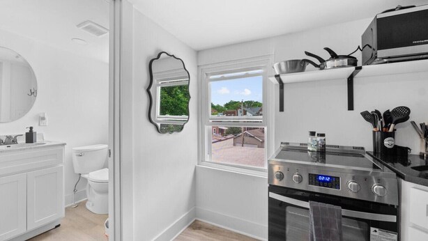 Una cocina moderna con horno empotrado, una ventana con vistas y un inodoro blanco.