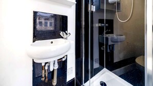 Uma casa de banho moderna com uma sanita à vista, uma lavatório branco e um cabine de duche em vidro.