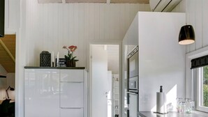 Una cocina moderna con armarios blancos, una lámpara colgante negra y vista al área de comedor.