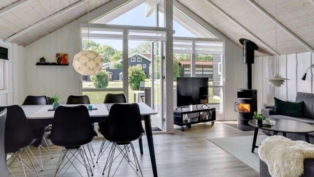 Un loft espacioso con techos altos, una zona de comedor con sillas modernas, una chimenea y un ventanal con vistas al exterior.