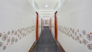 A hallway with a black floor, white walls, and a ceiling with recessed lighting. - Deluxe the Paradise Guest inn (Nellore)