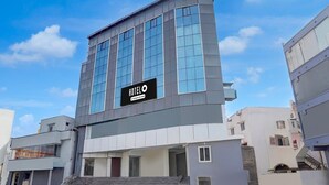 A modern hotel with a prominent sign, a staircase leading to the entrance, and a clear sky. - Deluxe the Paradise Guest inn (Nellore)