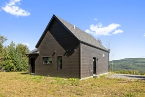 A single-story wooden house with a gabled roof, a chimney, and a small porch.
