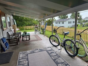 A covered porch with a table, chairs, a bicycle, and a view of a house in the background. - "Swanbreeze West" Prime Location in Adorable Historic Swansboro - Walk to Town (Swansboro)