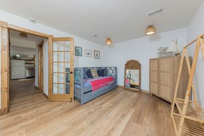 Une pièce avec un lit, un plancher en bois, une armoire et, au fond, un petit coin cuisine.