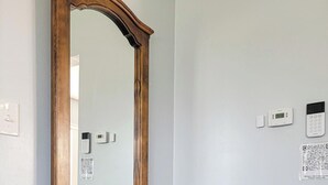 Una consolle in legno con uno specchio, una pianta in vaso e un termostato fissato alla parete.