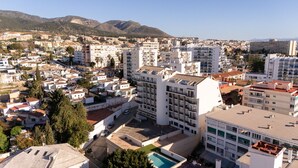 Un paisaje urbano costero con una combinación de edificios residenciales y comerciales, incluyendo un edificio blanco destacado con piscina en la azotea.