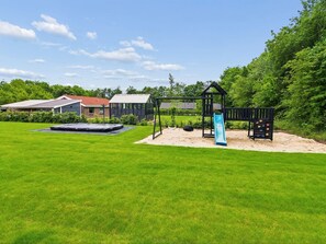 Ein Garten mit Trampolin, Schaukel und Rutsche.