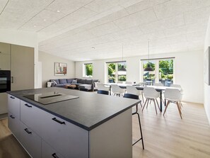 A modern kitchen with a central island, dining area with chairs, and a sofa. - "Biergh" - 30km from the sea by Interhome (Toftlund)