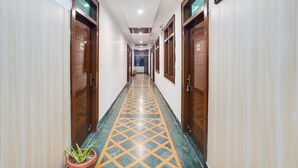Un pasillo de hotel con puertas de madera, piso estampado y una planta en maceta.