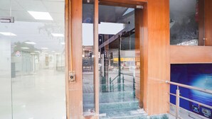 Una entrada de edificio con puerta de cristal, escalera metálica y barandilla de metal.