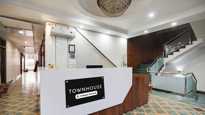 Un mostrador de recepción con la leyenda 'TOWNHOUSE Company Serviced', una escalera y plantas en macetas.